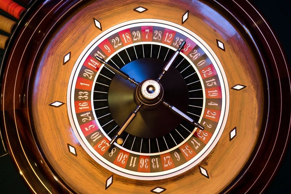 Roda roulette di meja kasino dengan dealer yang melayani permainan