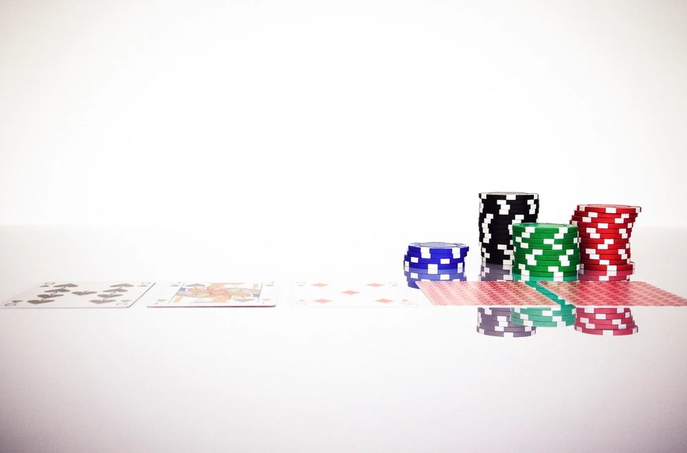 Keping poker dan kartu remi tersebar di atas meja permainan