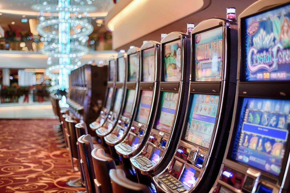 Deretan mesin slot berlampu warna-warni di lantai kasino